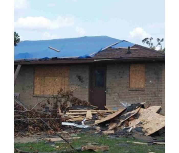 a picture of a house right after a storm where the roof has been taken off
